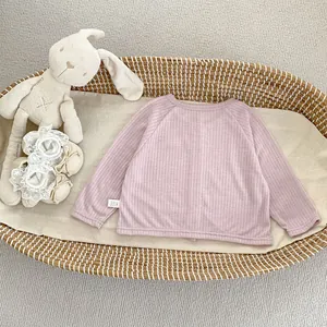 Gros plan du cardigan pare-soleil lilas pour bébé dans un panier avec un lapin en peluche