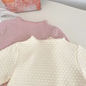 Detailansicht der Baby-Jacquard-Strickoberteile mit Wellensaum in Rosa und Creme
