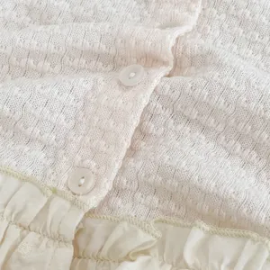 Dettaglio macro del cardigan per neonati con trama in maglia a fiori e bottone