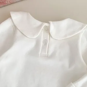 Dettaglio camicia bianca per bambini con colletto Peter Pan e piccoli bottoni curati