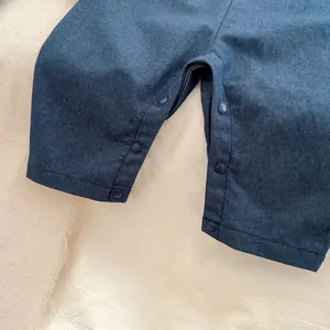 Detail view of the snap buttons and denim fabric on the infant boys' jumpsuit set