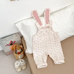 Detail eines geblümten Baby-Stramplers mit Hasenohr-Trägern und Spitzenschuhen
