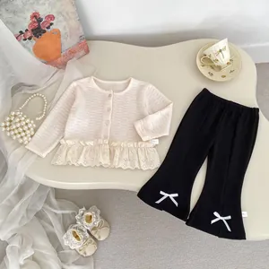 Set cardigan in maglia per bambina con pizzo e pantaloni a zampa neri su sfondo elegante