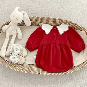 Dettaglio tutina neonato rossa a maniche lunghe con colletto a onde in una culla
