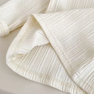 Detailed macro view of the cream-colored ribbed knit fabric texture and high-quality stitching