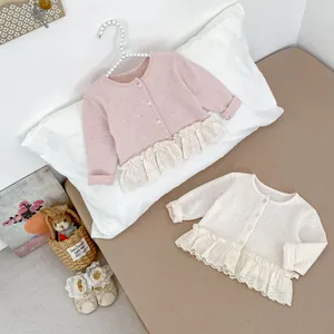 Dettaglio di cardigan in maglia per neonati con trama a nido d'ape e bordo in pizzo