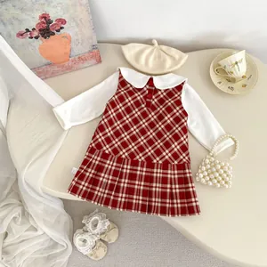 Dettaglio flat lay di un abito a quadri da bambina con scarpe di pizzo e borsa di perle