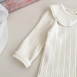 Detail of baby white long sleeve shirt showing delicate lace collar and ribbed knit texture