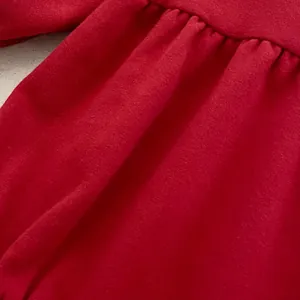 Dettaglio tutina neonato rossa in velluto con polsini elastici increspati e tessuto morbido