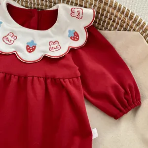 Dettaglio tutina neonato rossa con colletto bianco ricamato e motivi a forma di coniglio