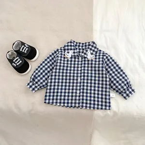 Detail of blue plaid baby shirt with duck embroidery and black canvas infant shoes