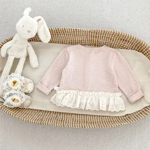 Dettaglio del cardigan rosa per neonata con pizzo bianco e trama in maglia a nido d'ape