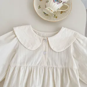 Detail eines cremefarbenen Babykleides mit Peter-Pan-Kragen und plissierter Taille