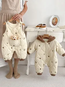 Detail of infant quilted rompers with star embroidery and brown plush bear accents
