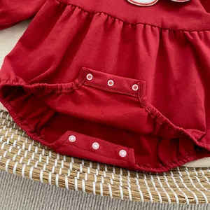Dettaglio dei bottoni automatici sul cavallo di un body neonato rosso in maglia di cotone