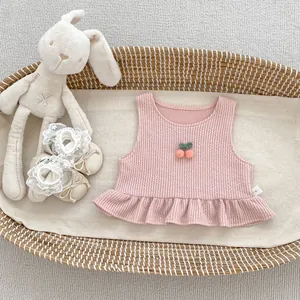 Detail of pink knitted baby vest with cherry embroidery and matching infant shoes