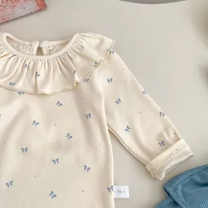Detail of cream baby bodysuit with lace collar and blue bow print pattern