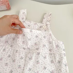 Detail der floralen Baby-Latzhose mit weißen Knöpfen und Vordertasche auf weichem Baumwollstoff