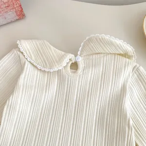 Detail of baby girl cream knit shirt featuring lace Peter Pan collar and ribbed texture