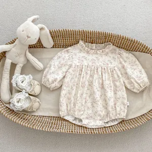 Close-up of baby floral romper with ruffle collar on a soft knit background