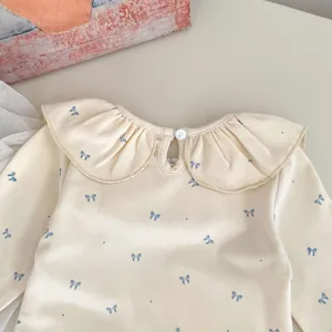 Detailed view of baby ribbed top with ruffled collar and blue bow print patterns