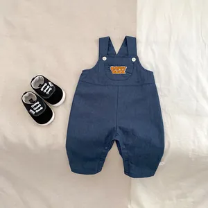 Detailed flat lay of navy blue baby overalls with Happy Duck embroidery and canvas shoes