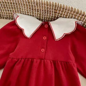 Dettaglio di tutina rossa neonata con colletto ricamato bianco e tre bottoni