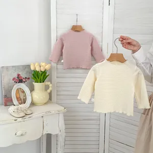Detailansicht der Strickstruktur und der dekorativen Rüschenkanten an Baby-Unterhemden