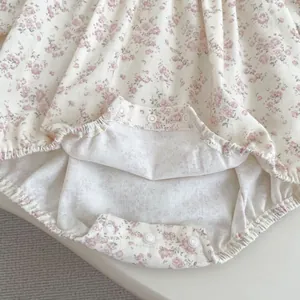 Detail of snap button closures and elastic cuffs on floral baby bodysuit