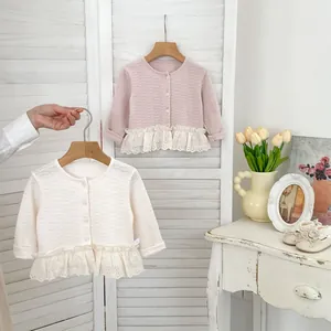Dettaglio cardigan in maglia per neonata con bordo in pizzo e trama a nido d'ape