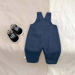 Flat lay of navy blue baby overalls with cross-back straps and matching canvas shoes