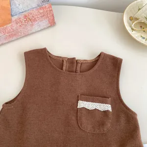 Detail of waffle knit brown vest with lace pocket and back snaps for baby girls