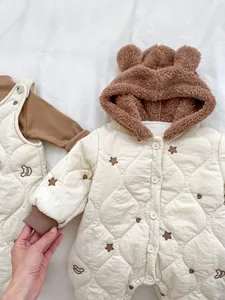 Detail of baby quilted romper featuring plush bear ear hood and bear embroidery