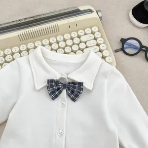 Detail of baby boy white shirt with checkered bow tie and soft cotton fabric texture