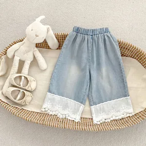 Detail of girls' light blue denim wide-leg pants with elegant white lace embroidery hem