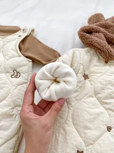 Detail of baby winter jumpsuit showing quilted fabric and thick white fleece lining