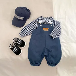 Flat lay of baby boy navy suspender pants set with plaid shirt, hat and sneakers