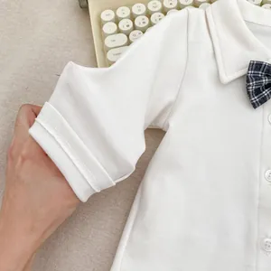 Close-up of white cotton baby shirt featuring a checkered bowtie and ribbed cuffs