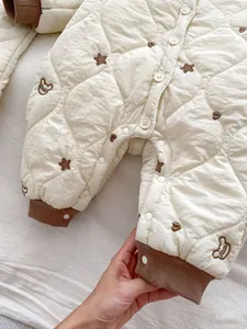 Detail of baby quilted romper showing bear patterns and brown ribbed cuffs