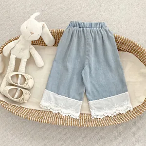Close-up of girls light blue wide leg jeans with delicate white lace embroidery on the hem