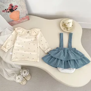 Detail of baby floral blouse with peter pan collar and blue corduroy pinafore dress set