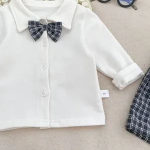Close-up of baby boy white dress shirt with checkered bowtie and size 66 label