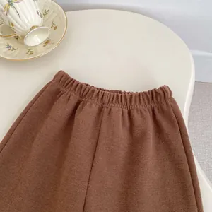 Detail of children's brown elasticated trousers with textured knit fabric on a table