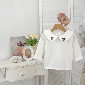 Dettaglio maglia neonata bianca a maniche lunghe con colletto Peter Pan e ricamo ciliegia