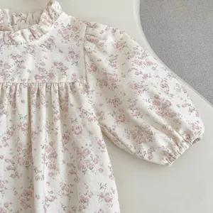 Detail of floral baby bodysuit featuring ruffled collar and delicate puff sleeves