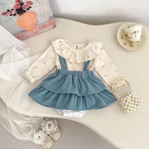 Close-up of baby girl outfit with floral lace collar and blue corduroy pinafore dress