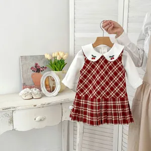Dettaglio del colletto Peter Pan ricamato con ciliegie e vestito a pieghe scozzese rosso