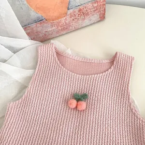 Detail of pink ribbed infant vest featuring cute knitted cherry accents and soft texture