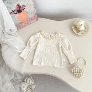 Detail van crème ribgebreide baby top met kantkraag en pofmouwen in Franse retrostijl