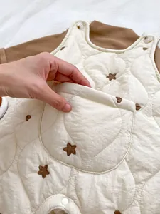 Detail of quilted baby romper featuring brown star embroidery and a front utility pocket
